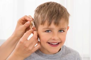 Hearing aid being put on young boy.