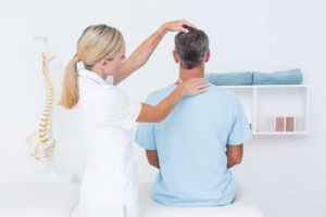 Female chiropractor checking alignment of man's neck.