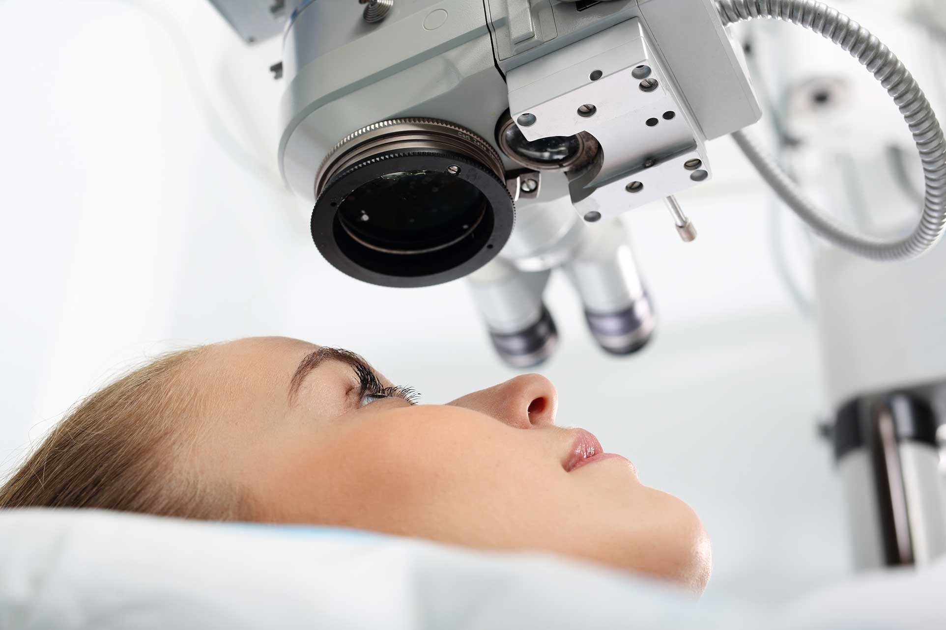 Woman lying under lens of machine for eye care